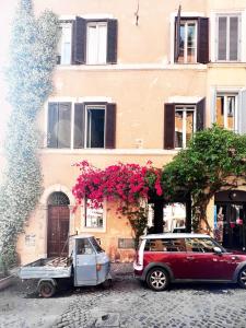 ローマにあるRomantic Wellness Apartment COLOSSEOの花の咲く建物の前に二台駐車