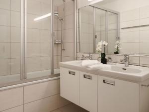 a white bathroom with a sink and a mirror at Apartment Allod Park Haus C 205 by Interhome in Davos