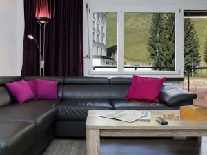 a living room with a black leather couch and pink pillows at Apartment Allod-Park-22 by Interhome in Davos