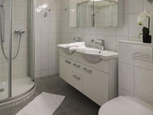 a white bathroom with a sink and a shower at Apartment Allod-Park-22 by Interhome in Davos