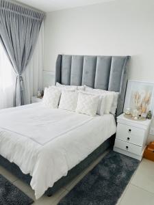 a bedroom with a large white bed with a gray headboard at Apollo one bedroom in Sandton