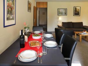 Apartment Allod Park Haus B E01 by Interhome في دافوس: طاولة غرفة الطعام مع غطاء الطاولة الأسود والأطباق وكؤوس النبيذ