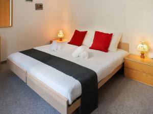 1 dormitorio con 1 cama grande con almohadas rojas en Apartment Allod Park Haus B E01 by Interhome, en Davos