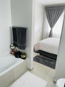 a white bathroom with a bed and a bath tub at Apollo one bedroom in Sandton