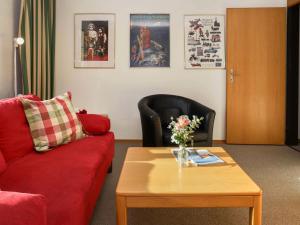 Apartment Allod-Park-48 by Interhome في دافوس: غرفة معيشة مع أريكة حمراء وطاولة قهوة