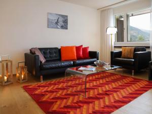 ダボスにあるApartment Allod Park Haus C 705 by Interhomeのリビングルーム(黒い革張りのソファ、オレンジの枕付)