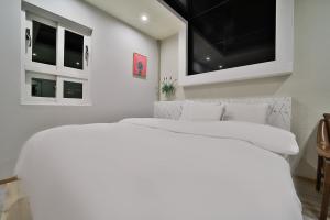a white bedroom with two beds and windows at Evian Hotel in Gyeongsan