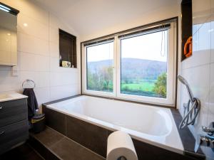 a bathroom with a tub and a large window at Chalet Haus am Fluss by Interhome in Wahmbeck