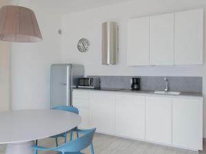 ブレンゾーネにあるApartment La Maison Blanche-1 by Interhomeのキッチン(白いキャビネット、テーブル、冷蔵庫付)