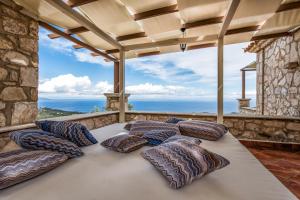 una camera con un grande letto con cuscini su un balcone di Villa Armos a Skinária