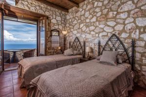 Dos camas en una habitación con pared de piedra. en Armos Stone Villa - Private Pool & Sea Views, by ZanteWize, en Skinária