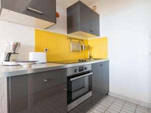 ラ・グランド・モットにあるApartment Poséidon by Interhomeの黄色の壁と灰色のキャビネットが備わるキッチン