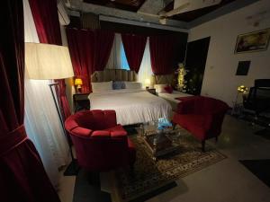 a bedroom with a bed and two red chairs at La casa Luminosa Hotel in Islamabad