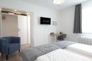 1 dormitorio con 1 cama y 1 silla azul en Hotel Kühl, en Neumünster