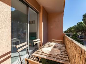 a balcony with a wooden table and chairs on a balcony at Apartment Hélios by Interhome in Le Lavandou