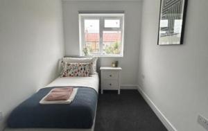 a small bedroom with a bed and a window at London Stunning Three Bedroom House in Mitcham