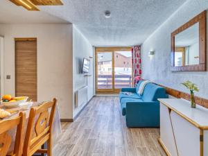 uma sala de estar com um sofá azul e uma cozinha em Apartment Altineige-4 by Interhome em Val Thorens