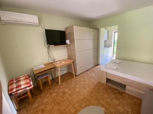 Kleines Zimmer mit einem Bett und einem Schreibtisch mit einem TV. in der Unterkunft Porat 2 in Poreč