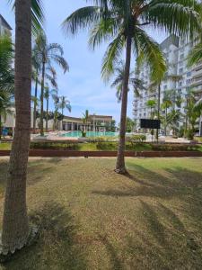 two palm trees in a park next to a building at Newly refurbished Cozy PD Bayview Apartment with Ocean View in Port Dickson