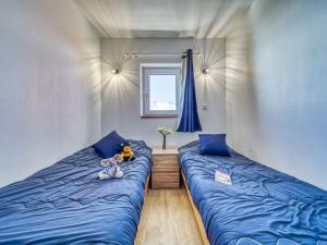 a bedroom with two beds with blue sheets and a window at Apartment Altineige-6 by Interhome in Val Thorens