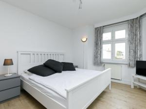 a white bedroom with a white bed and a television at Apartment Melchien 1 by Interhome in Zinnowitz