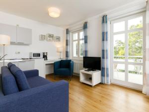 een woonkamer met een blauwe bank en een tv bij Apartment Zinnowitzer Hof-1 by Interhome in Zinnowitz