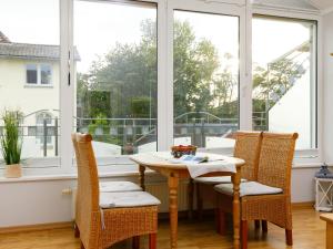 uma sala de jantar com mesa, cadeiras e janelas em Apartment App- 205 Luise von Preußen by Interhome em Zinnowitz