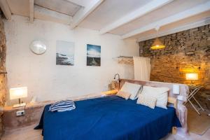 a bedroom with a blue bed and a stone wall at Can Polta in Santa Margalida