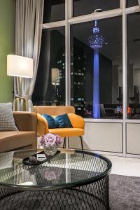 uma sala de estar com um sofá e uma mesa de vidro em Calm Sojourn, Sky Suites KLCC em Kuala Lumpur