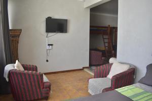 a living room with two chairs and a tv on the wall at BeachBums Lodge in Westbrook