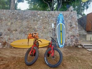 dos bicicletas y una tabla de surf junto a una pared de piedra en Tolani Resort Kui Buri, en Kui Buri