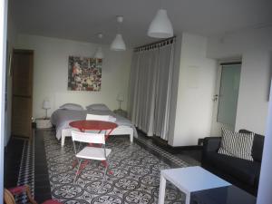 a living room with a bed and a red table at Le bonheur de la campagne à la ville - Grand studio en plein coeur de la ville in Nîmes