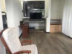 a living room with a white chair and a television at Refugio El Cacique in Guatavita
