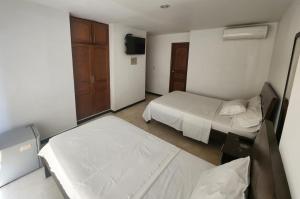 a small bedroom with two beds and a tv at Hotel Ciudad Capri in Cali +4 photos