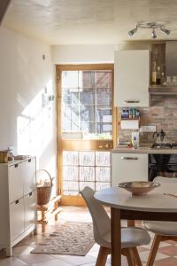 a kitchen with white appliances and a table with chairs at Valdastico Casetta in sasso con giardino in Pedemonte