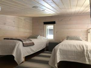 twee bedden in een kamer met houten wanden bij Villa Vilmala in Sääskilahti
