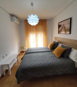 a bedroom with a large bed and a chandelier at Puerta del Sol - Plasencia in Plasencia +12 photos