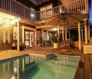 uma casa com piscina e guarda-sol em Lush Spacious Family Home between Beach & Town em Knysna