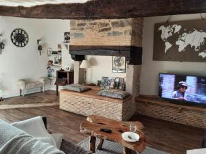 a living room with a tv and a couch and a table at Gite Du Passant Rennais avec balcon sur cour in Rennes