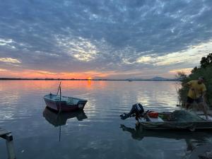 Ein Mann steht neben einem Boot auf einem See. in der Unterkunft Vila Horizont in Baks-Rrjoll