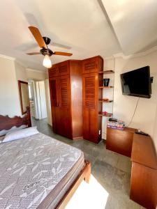 Apto 2 quadras da praia completo في غوارويا: غرفة نوم بسرير وتلفزيون بشاشة مسطحة