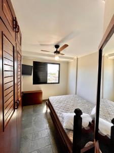 Apto 2 quadras da praia completo في غوارويا: غرفة نوم بسرير ومروحة سقف