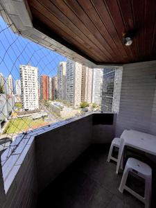 uma varanda com dois bancos e vista para a cidade em Apto com PISCINA 2 quadras da praia no Guarujá