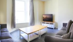 sala de estar con mesa y TV en 25 Newborough by Stay In Scarborough, en Scarborough