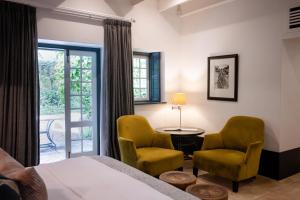 1 dormitorio con 2 sillas, 1 mesa y 1 cama en Grande Provence, en Franschhoek