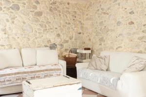 una sala de estar con 2 sofás blancos y una pared de piedra. en Valdastico Casetta in sasso con giardino, en Pedemonte