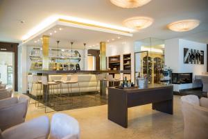 un soggiorno con bar e sedie bianche di Iris Porsche Hotel & Restaurant a Mondsee
