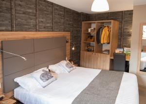1 dormitorio con 1 cama blanca grande y 2 almohadas en Logis Hôtel-restaurant Les Coudercous, en Saint-Chély-dʼAubrac