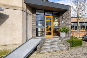 een gebouw met een gele deur en een trap voor de deur bij B&B De Tulpentoren in Roelofarendsveen