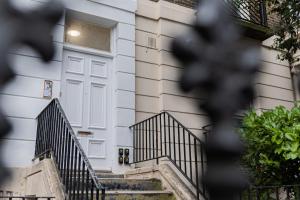 a white door on a house with stairs at One & Two Bedroom Apartments near Holloway Train Station by Belvilla in London